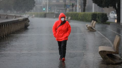 Una mujer pasea por el Paseo Marítimo de A Coruña entre la lluvia