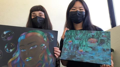 Dos alumnas del IES de Sar muestran las pinturas que donaron para la subasta de arte multidisciplinar que acoge hoy el centro sociocultural de Sar con fines solidarios, organizada por su centro y el Espazo Vecial de Sar