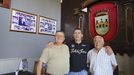 Fernando y Olegario, fundadores de este bar, posan junto a José María frente al busto y los cuadros que recuerdan su historia.