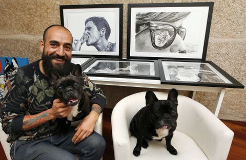 Marcos Mguez Puhinger, con su perra Pepa en su regazo y al lado el hijo de esta, Lomu, rodeados por algunos de sus dibujos. 