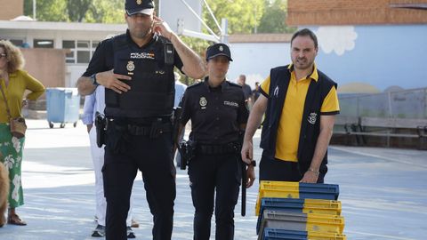 Un cartero que lleva votos por correo llega escoltado por dos agentes de la policía a un colegio electoral de Madrid 