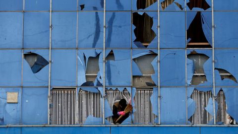 Un hombre quita un cristal roto de un edificio de Kabul.