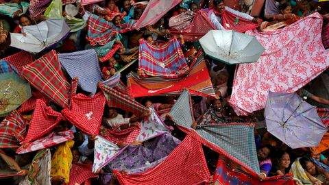 Devotos hindes extienden ropas y paraguas para recibir arroz distribuido por las autoridades del templo con motivo del festival Annakut en Calcuta (India)