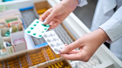 Imagen de archivo de un farmacutico con dos medicamentos en la mano.