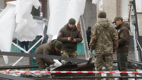 Agentes de policía inspeccionan los restos de un misil que cayó en la calle de Kiev.