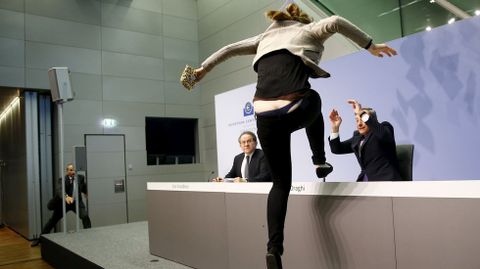 Una activista se sube a la mesa donde hablaba Mario Draghi en Francfurt, Alemania. 15 de abril. 
