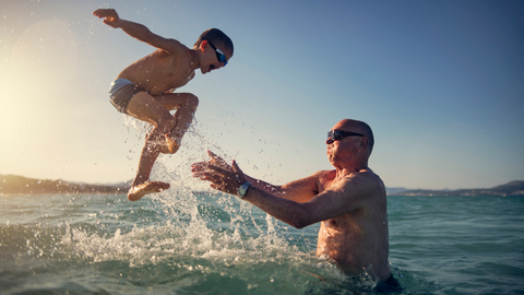Un abuelo juega con su nieto en el agua.