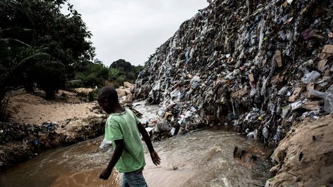 Un nio camina a travs de un ro a orillas de un vertedero en Kinshasa (Repblica Democratica del Congo).