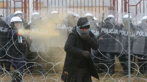 Un agente polaco repele con gas lacrimgeno a un migrante en el cruce de Kuznica.