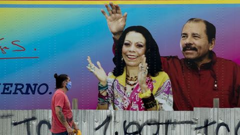Un hombre pasa frente a un cartel del presidente Daniel Ortega y su esposa Rosario Murillo