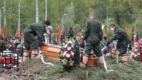 Sepultureros proceden a enterrar a un fallecido por coronavirus en un cementerio moscotiva