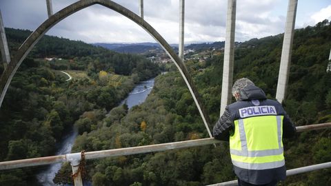 Un polica nacional observa el ro Ulla desde el puente de Gundin, en Vedra