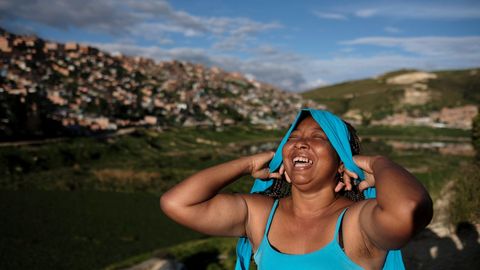 Una mujer colombiana, que participar en el proceso para aclarar los crmenes durante el conficto civil de su pas, re mientras se coloca una diadema en las afueras de Bogot