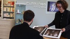Un padre, consultando un álbum de fotografías de primeras comuniones en una tienda de Lugo.