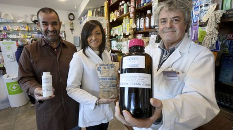 Eduardo Esteban y dos trabajadores de su farmacia, mostrando algunos de los productos que les convierten en un negocio único.