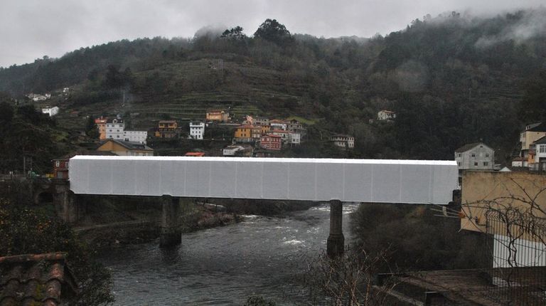 El puente ferroviario presenta estos días un aspecto muy poco común, oculto una tela para evitar que caiga material al río