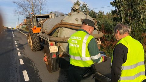 Un guardia civil de Trfico examina la documentacin de un tractor en una carretera gallega