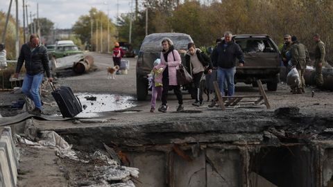 Una familia cruza junto a un puente dañado en la ciudad liberada de Kipiansk, en el este de Járkov