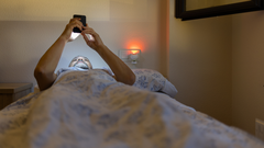 Una persona consulta el m�vil en cama.