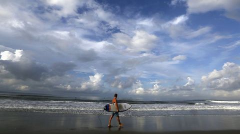 Un turista con su tabla de surf en Bali. 