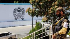 Un taliban monta guardia frente a la antigua embajada de Estados Unidos,en cuya pared aparec pintado el sello del Emirato islmico de Afganistn.