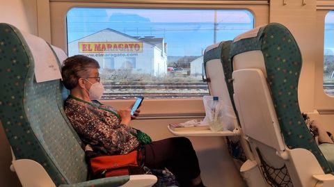 Una viajera del Alvia Vigo-Barcelona, entretenida leyendo mientras el tren sale de Astorga