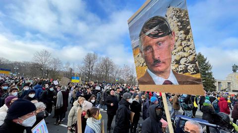 Una persona sostiene un cartel que representa al presidente ruso Vladimir Putin como Adolf Hitler mientras los manifestantes se reúnen durante una protesta contra la guerra frente al monumento a la guerra soviética en el parque Tiergarten, en Berlín, Alemania.