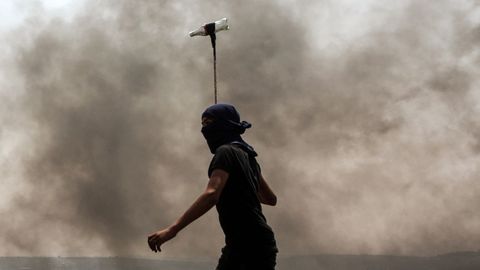 Un manifestante palestino lanza una botella de cristal a las fuerzas de seguridad israeles