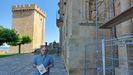 Jorge Vila con un ejemplar de su libro ante la torre del homenaje y el antiguo convento de San Vicente do Pino, actual parador