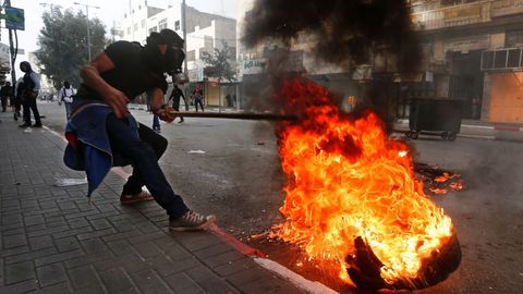 Varios palestinos lanzan neumticos ardiendo a soldados israeles durante una protesta en Hebrn
