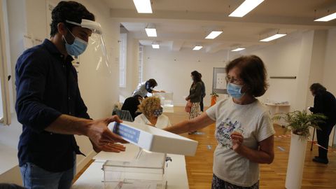 Una electora deposita su DNI en una bandeja en el Centro cívico Cidade Vella de A Coruña