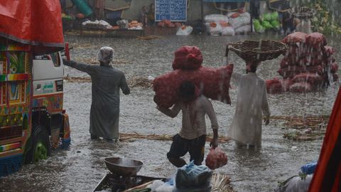 Vecinos de Lahore (Pakistán) ponen a salvo algunas mercancías por las lluvias del monzón.