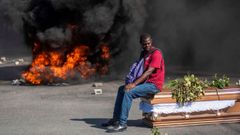 Un hombre permanece sentado sobre el fretro de una de las vctimas de las protestas de febrero contra el Gobierno de Jovenel Moise