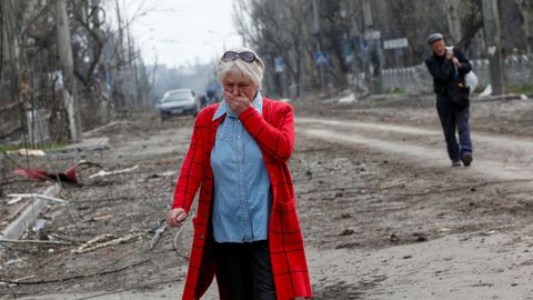 Una mujer se emociona en una calle de Mariúpol donde quedan a la vista los destrozos 