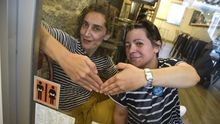Mara Mario y Marisol Fernndez, con la pegatina del proyecto Preciso pasar que exhibe el Tbula Rara de Pontevedra, el primer local en sumarse a la iniciativa