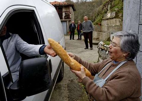 Concepción compra el pan ante la atenta mirada de su esposo y vecinos.