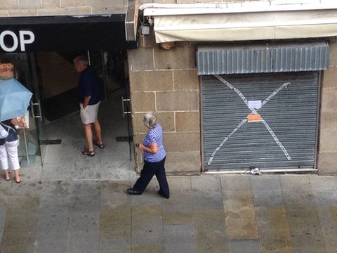 Unos turistas pasean entre los comercios precintados en la redada del miércoles
