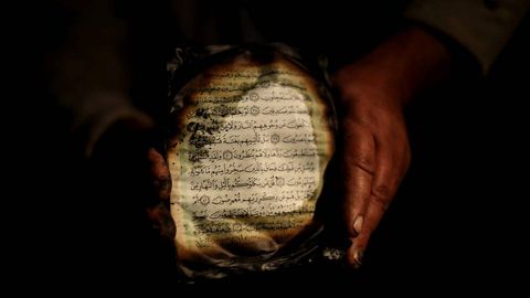 Un palestino muestra lo que queda de una copia del Corán mientras inspecciona los daños registrados en una mezquita de Cisjordania.