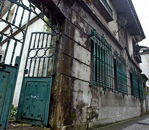 El edificio está a la entrada de la calle, al lado de la iglesia parroquial y pegado a otras casas.