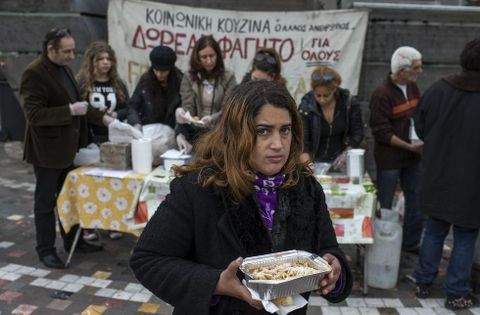 Una mujer en un puesto de reparto de comida, a cargo de una oenegé, en Atenas.