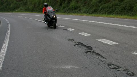 Un motoristas pasa por la carretera llena de baches en la que un joven peridó la vida el pasado sábado.