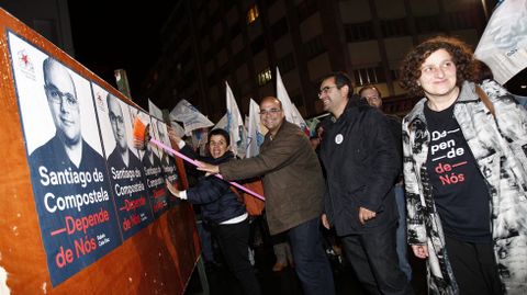 Rubén Cela, del BNG, pega el cartel electoral de su partid en Santiago