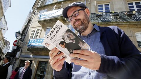 Martiño Noriega, de Compostela Aberta, ojea un libro de Conde Roa durante un Bookcrossing en praza Cervantes