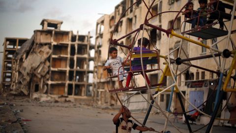 Nios palestinos disfrutan de una noria cerca de edificios residenciales, destruidos el verano pasado durante una guerra de 50 das, al norte de la Franja de Gaza