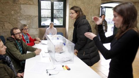 Un hombre con discapacidad auditiva preside una mesa electoral mientras la interprete le ayuda con el lenguaje de signos en Rois, A Coruña
