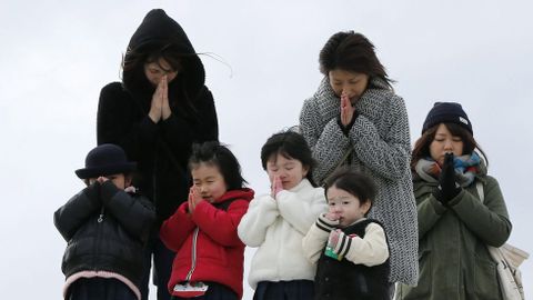 Varias personas guardan un minuto de silencio en memoria de las víctimas.