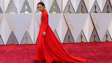 Ruth Negga lució un fabuloso vestido con cola, de manga larga y cuello de encaje con reminiscencias isabelinas firmado por Valentino, un modelo rojo que conjuntaba con tiara y pendientes granates