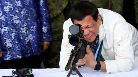 El presidente filipino Rodrigo Duterte chequea la mirilla de un rifle de francotirador durante una ceremonia militar. 