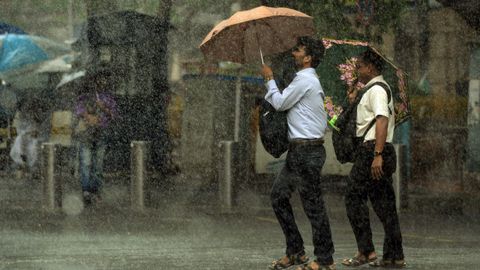 Peatones indios protegindose con su paraguas de la fuerte lluvia en Mumbai, India