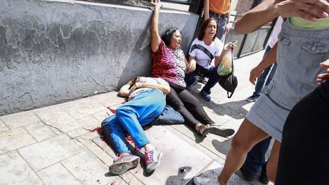 Dos mujeres yacen en el suelo tras un enfrentamiento entre chavistas y opositores